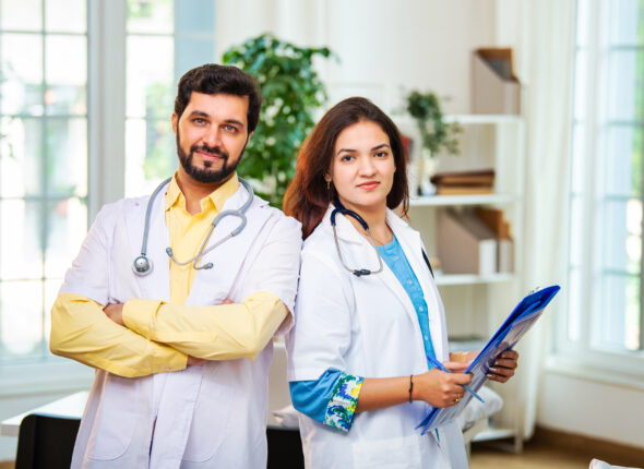 Indian Professional Indian Asian doctors standing together in a clinic, smiling with folded arms